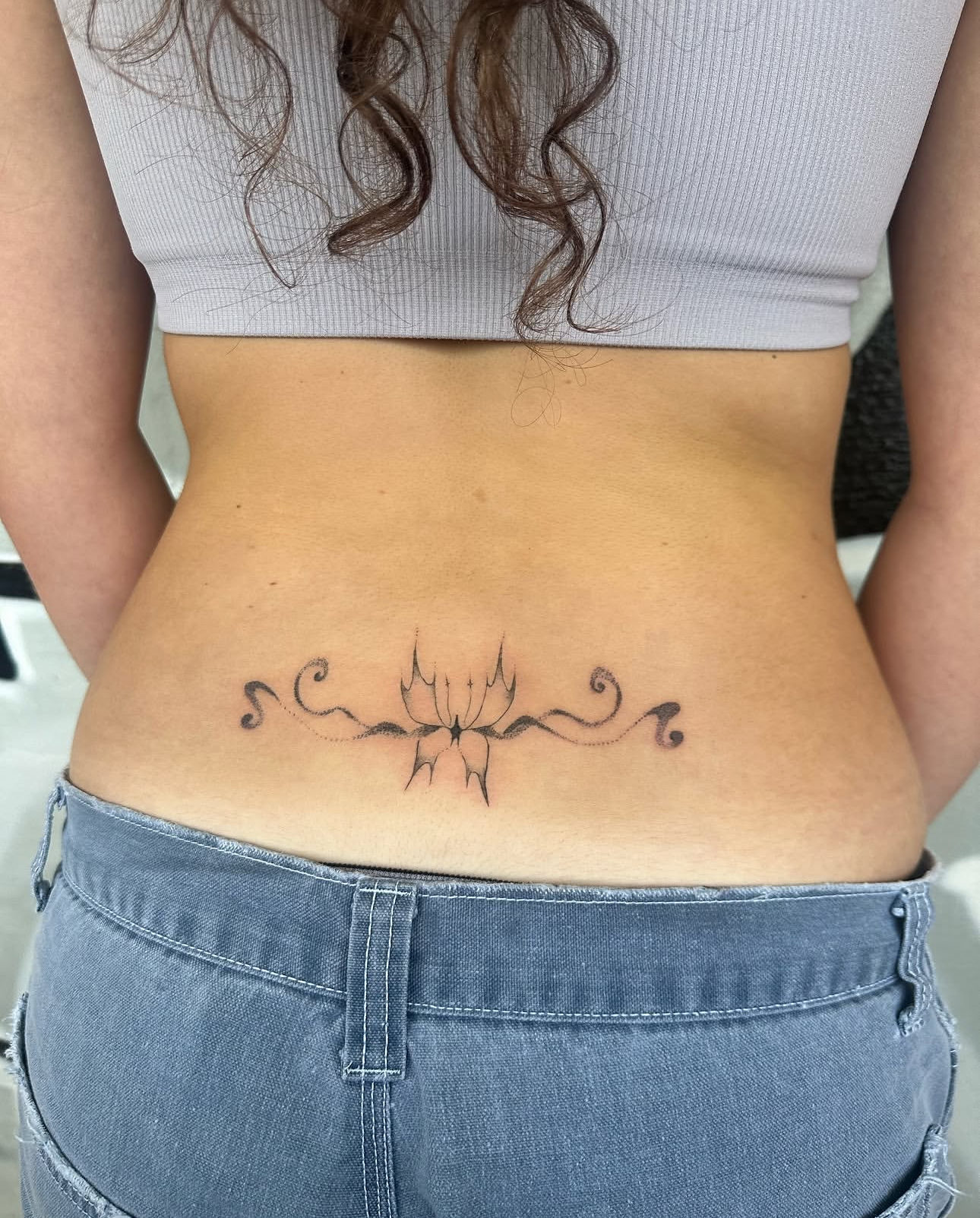 Ornamental lower back lotus tattoo by Lauren